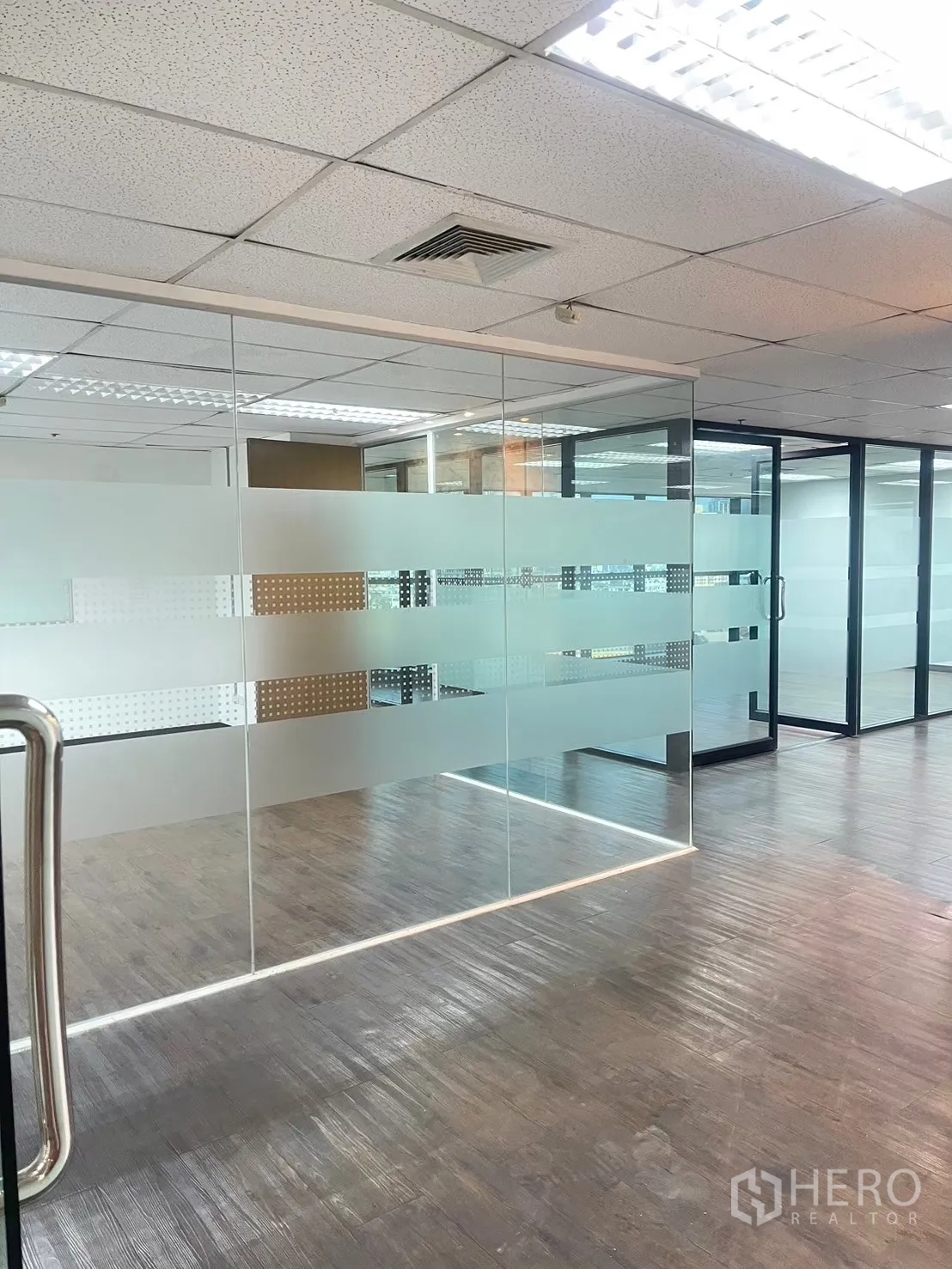 办公室 for rent in Watthana, Bangkok - 室内玻璃墙附磨砂条纹，木色地板与吊顶灯具。