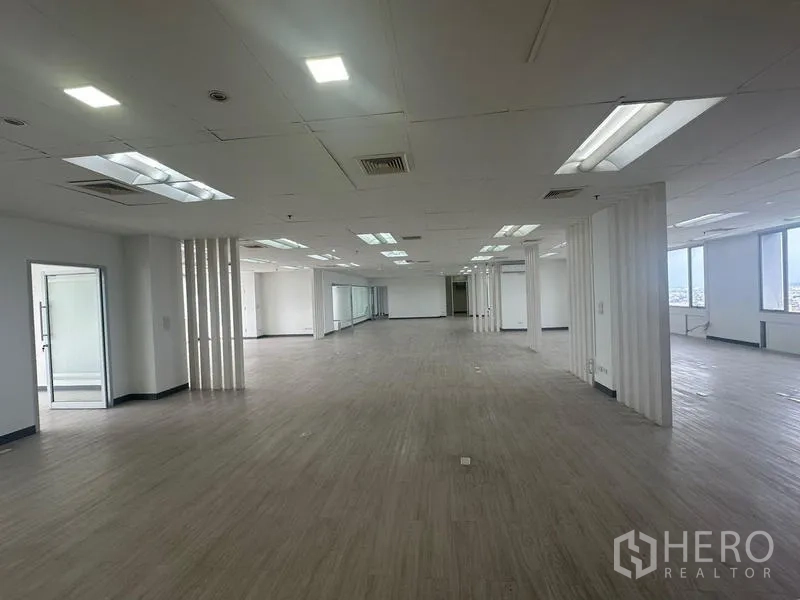 สำนักงาน ให้เช่า - พื้นที่ออฟฟิศกว้าง ฝ้าเพดานแขวนพร้อมไฟ และช่องหน้าต่างหลายจุด