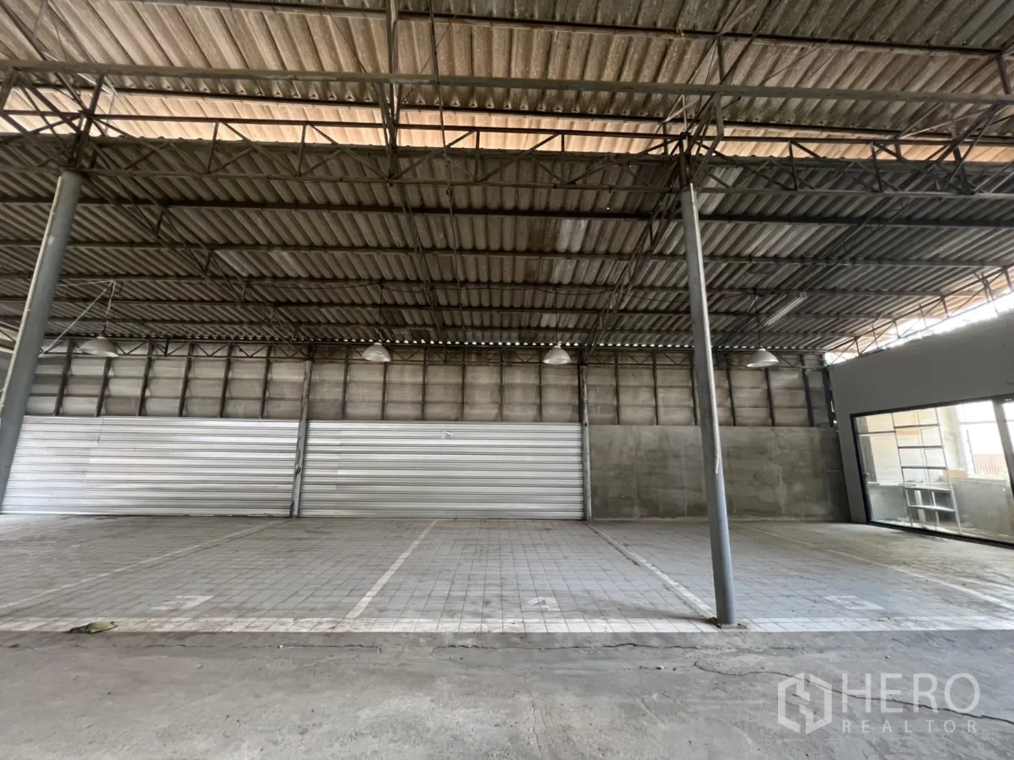 คลังสินค้า ให้เช่าในKhlong Toei, Bangkok - โซนโกดังโล่ง ผนังคอนกรีต พื้นกระเบื้อง และประตูม้วนโลหะ