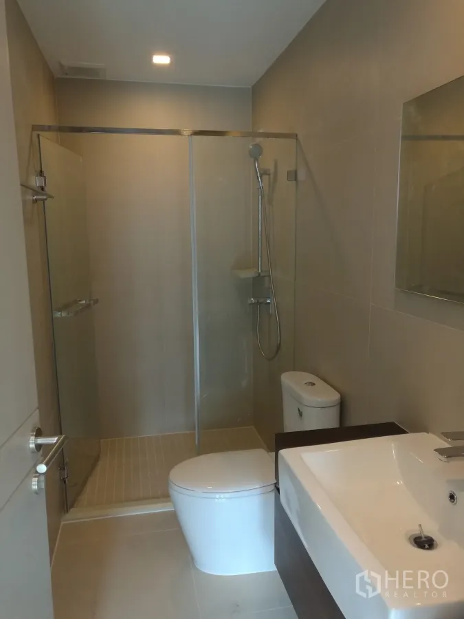 Townhouse for rent or sale in Suan Luang, Bangkok - Modern bathroom with glass shower enclosure, wall-hung sink and toilet.