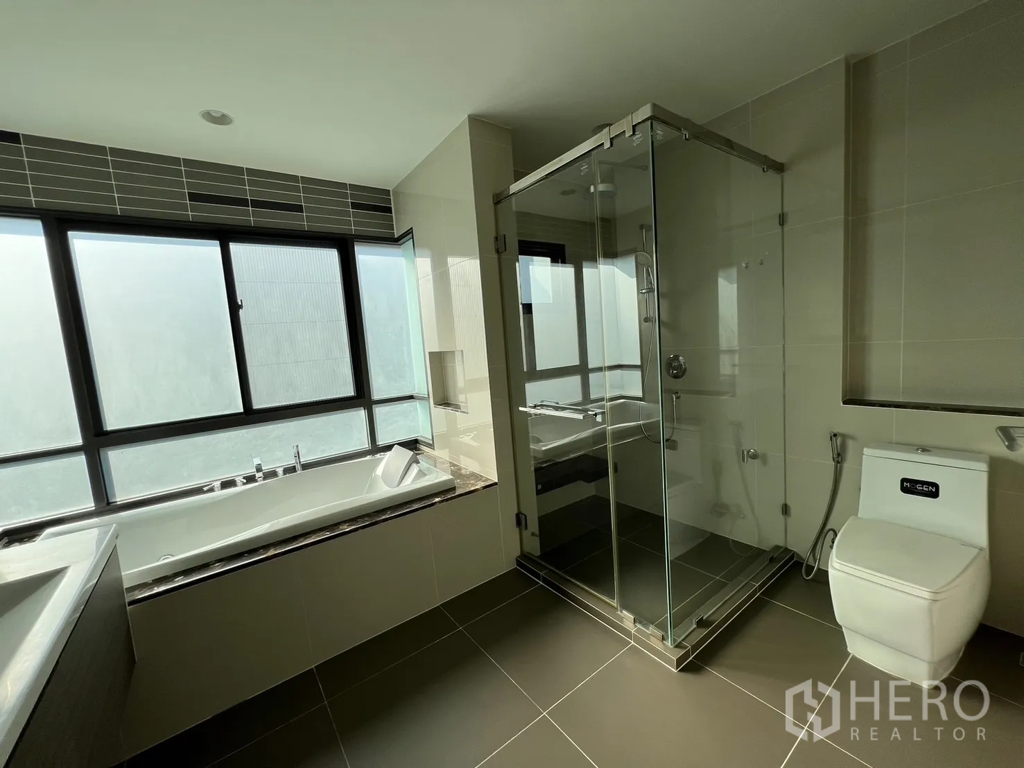Detached House for rent or sale in Bang Kapi, Bangkok - Master bathroom with glass shower cubicle, toilet and tub in view.