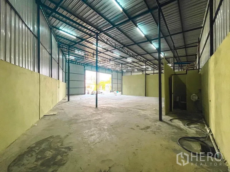 Warehouse for rent in Sai Mai, Bangkok - Deep interior perspective highlighting roof framing, columns and front entry.