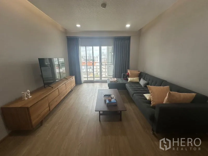 Condominium for rent - Living room with L-shaped sofa, TV console and balcony offering city views.