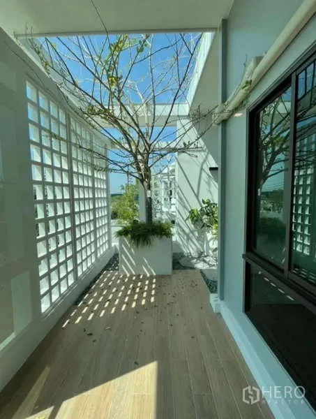 Detached House for rent in Samut Prakan - Shaded terrace with lattice wall, planter tree and wood-look deck.