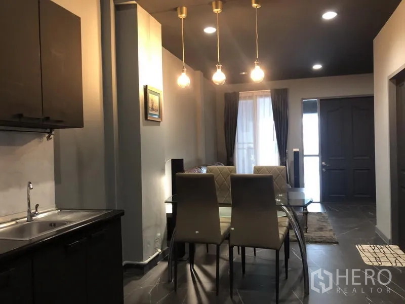 ทาวน์เฮาส์ ให้เช่าในBang Kapi, Bangkok - โต๊ะอาหารกระจกใต้โคมไฟแขวน มองไปยังประตูทางเข้าและผ้าม่าน