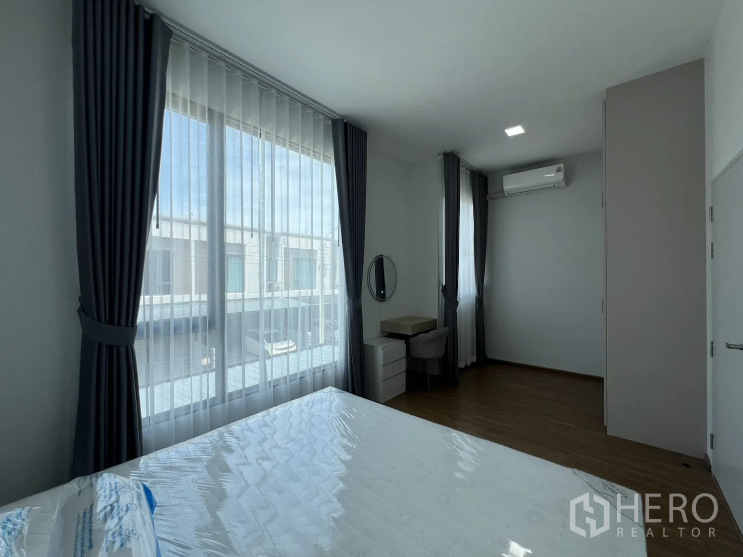 Townhouse for rent in Bang Phli, Samut Prakan - Master bedroom with floor-to-ceiling windows, desk and air conditioner.