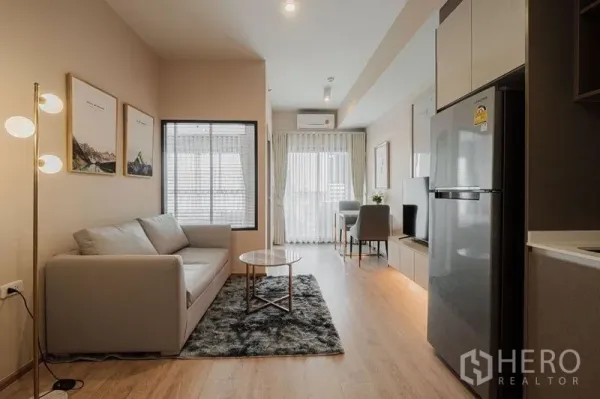 Condominium for rent - Another angle of the bright living room with sofa, rug, and kitchenette leading to the balcony.