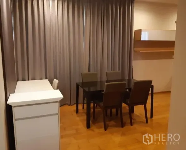 公寓 出租在Khlong Toei, Bangkok - 四人用餐区，玻璃餐桌、布艺餐椅与落地窗帘，木地板。