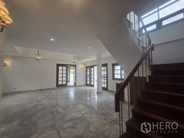 独立式住宅 出租在Phra Khanong, Bangkok - 起居区与木楼梯，多扇法式门与充足采光，铺大理石