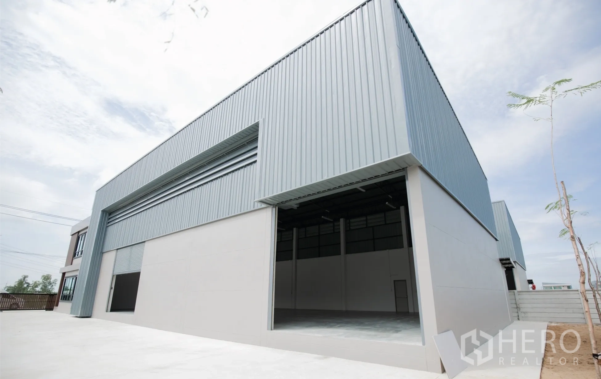 Factory for rent or sale in Nakhon Pathom - Large steel warehouse exterior with wide roller shutter and spacious loading apron.