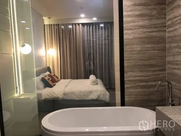 คอนโด ให้เช่าในWatthana, Bangkok - ห้องนอนมาสเตอร์พร้อมอ่างอาบน้ำเดี่ยว แสงไฟนุ่ม และผ้าม่านสูงจรดเพดาน