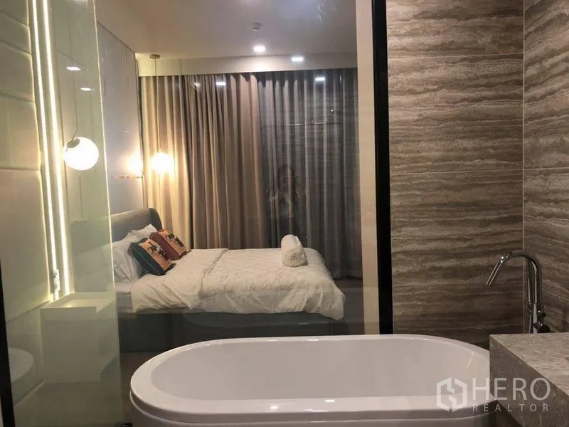 คอนโด ให้เช่าในWatthana, Bangkok - ห้องนอนมาสเตอร์พร้อมอ่างอาบน้ำเดี่ยว แสงไฟนุ่ม และผ้าม่านสูงจรดเพดาน