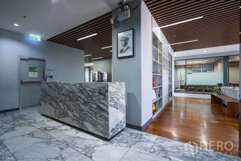 Office Space for rent - Reception area with marble counter beside shelving and wood floors.