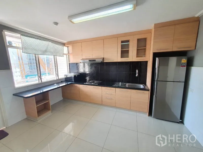 Condominium for rent in Watthana, Bangkok - Separate kitchen with light wood cabinetry, black backsplash, and a large window.