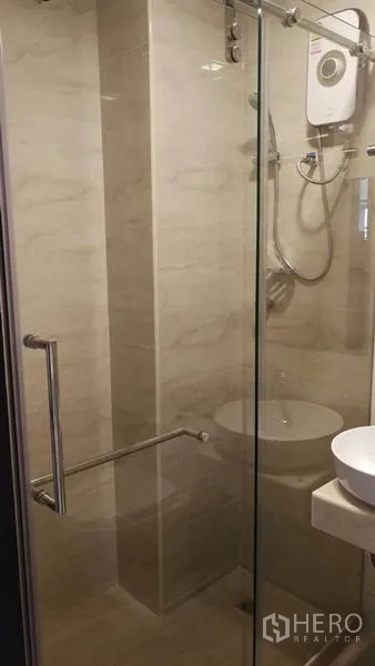 Townhouse for rent in Khlong Toei, Bangkok - Glass-enclosed shower with water heater and modern fixtures in tiled bathroom.