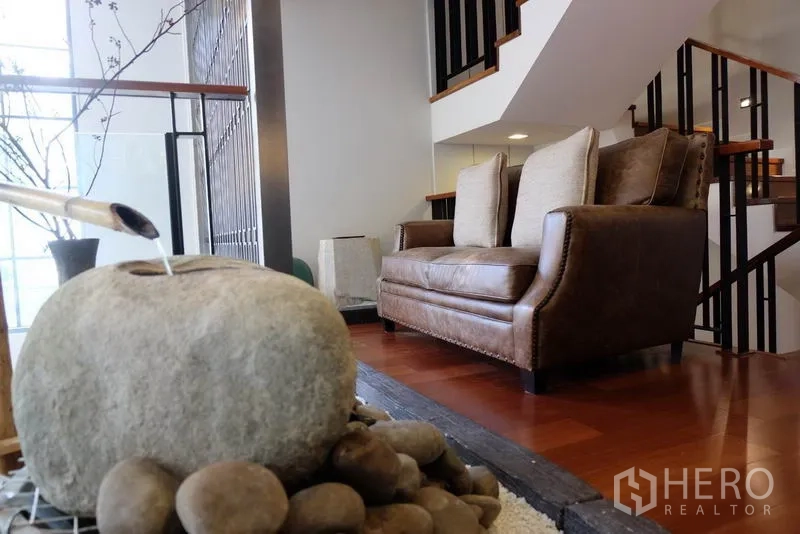 ทาวน์เฮาส์ ให้เช่าในKhlong Toei, Bangkok - พื้นที่พักผ่อนบริเวณบันได โซฟาหนังคู่ ข้างน้ำตกหินภายในบ้าน