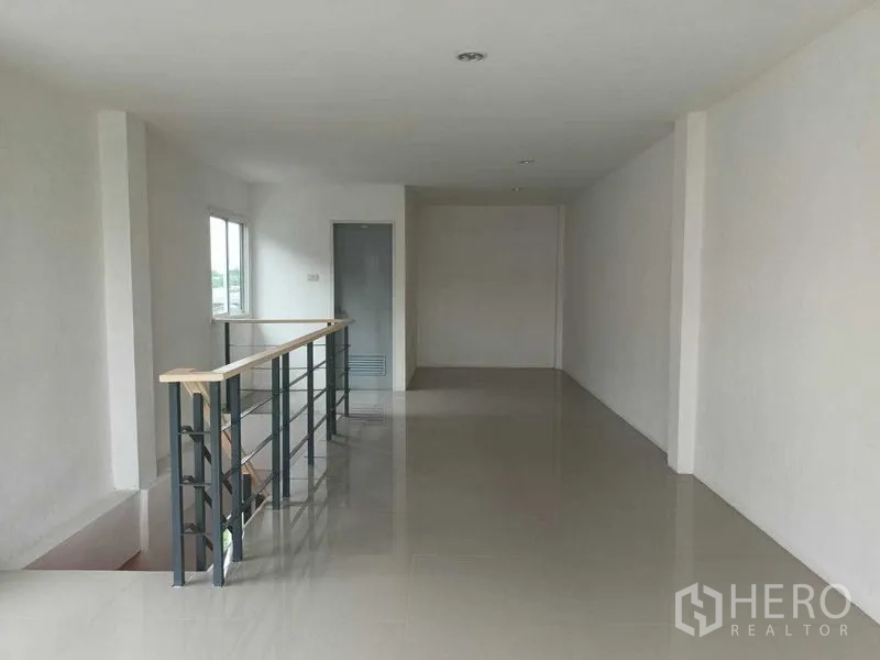 Shophouse for sale in Bueng Kum, Bangkok - Upper floor open-plan area with metal railing and window light in a modern shophouse.