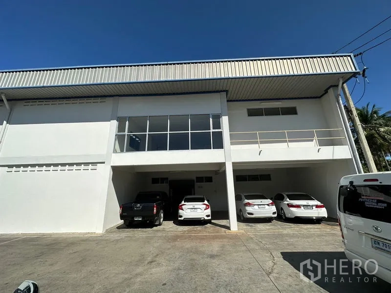 工厂 出租在Si Racha, Chon Buri - 工厂正立面，带有楼下覆盖式停车位与玻璃幕墙夹层办公室。