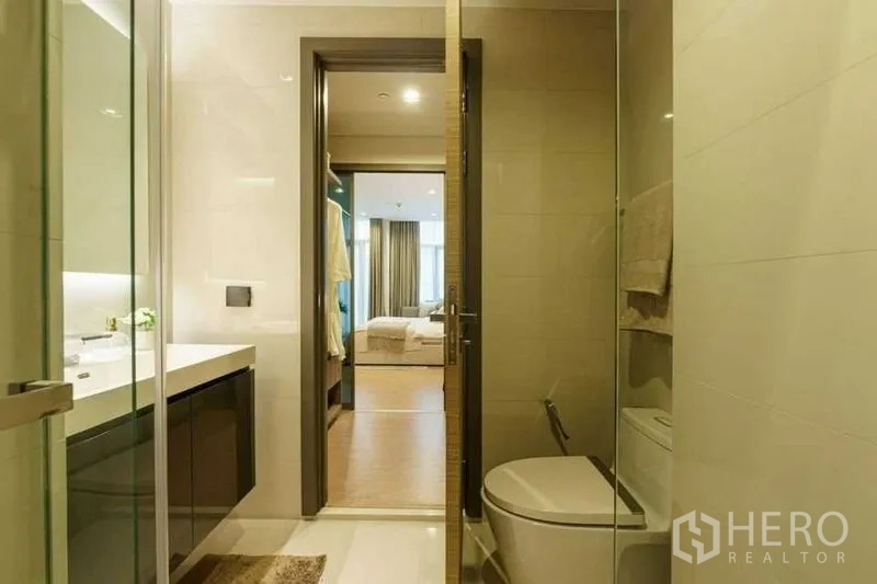 公寓 出售在Bang Rak, Bangkok - 采光良好的浴室，玻璃淋浴间、洗手台，门外可见卧室。