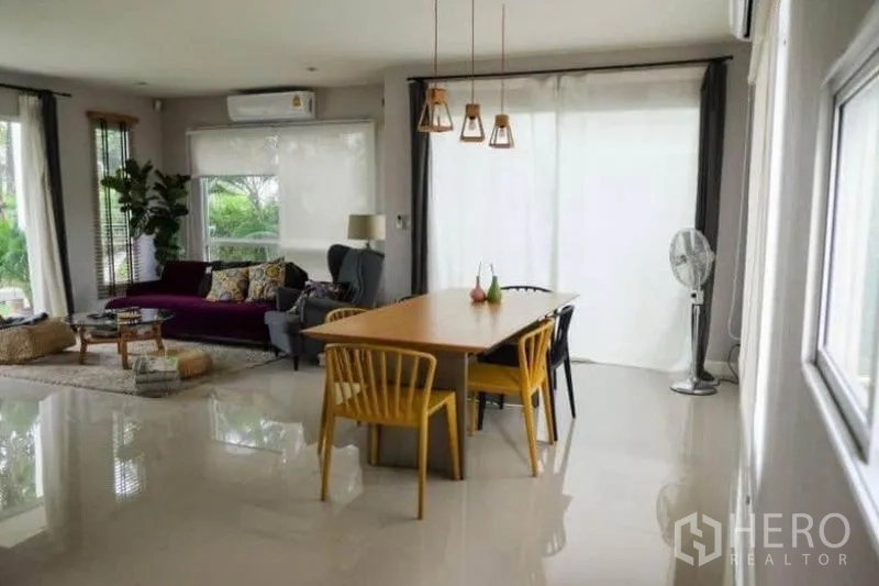 Detached House for rent or sale in Khlong Sam Wa, Bangkok - Bright open-plan living and dining area with glossy floors, large windows, pendant lights and colorful furniture.