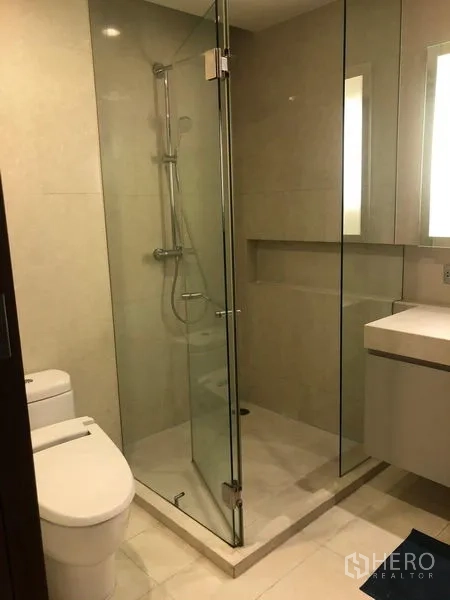 公寓 出租或出售在Watthana, Bangkok - 现代卫浴，玻璃淋浴房、马桶与简洁洗手台。