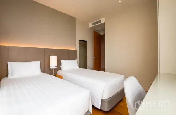 คอนโด ให้เช่าในBang Kho Laem, Bangkok - ห้องนอนเตียงเดี่ยวคู่ แสงนุ่ม โคมไฟหัวเตียง และโต๊ะทำงานบนพื้นไม้