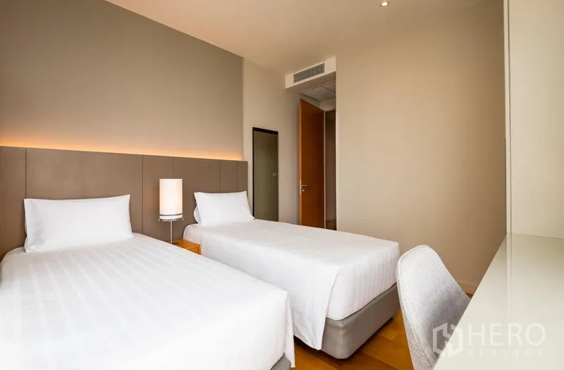 คอนโด ให้เช่าในBang Kho Laem, Bangkok - ห้องนอนเตียงเดี่ยวคู่ แสงนุ่ม โคมไฟหัวเตียง และโต๊ะทำงานบนพื้นไม้