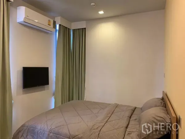 Condominium for rent or sale in Watthana, Bangkok - Primary bedroom with double bed, wall-mounted TV and air conditioning.