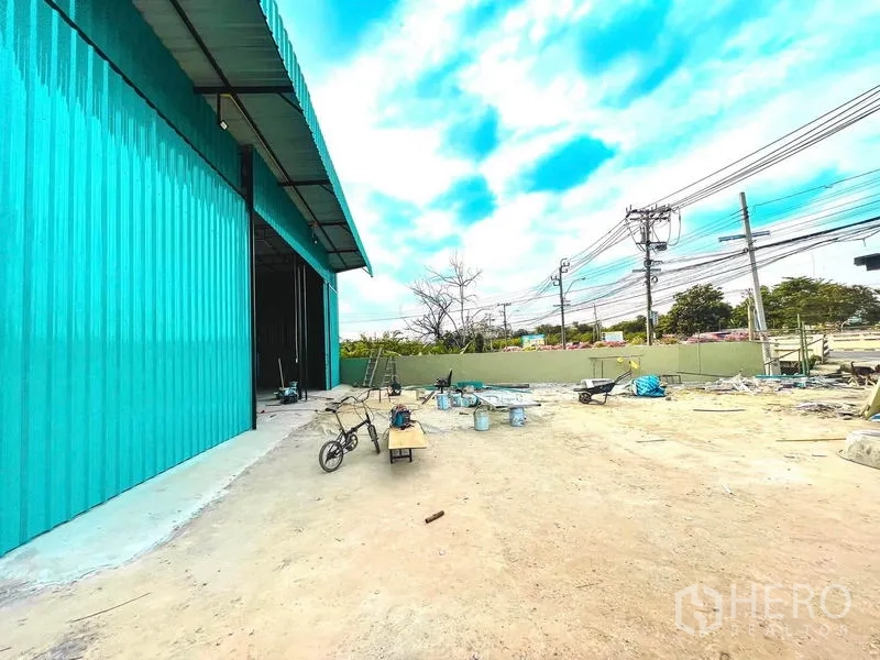 Warehouse for rent in Sai Mai, Bangkok - Large outdoor yard next to the warehouse facing the road and power lines.
