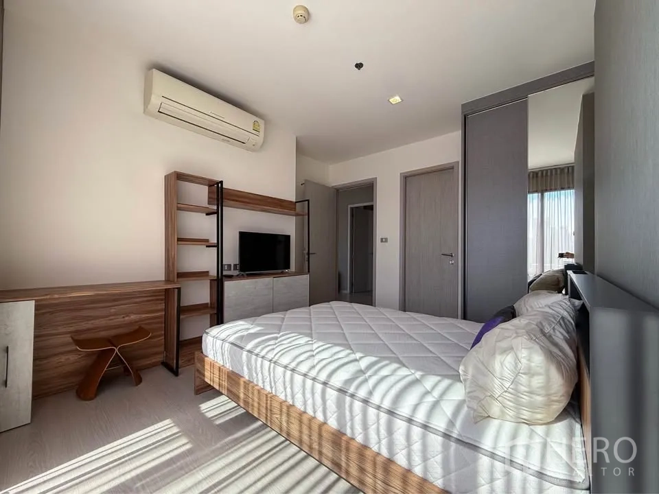 Condominium for rent in Khlong Toei, Bangkok - Sunlit room with bed, open shelving, TV and built-in wardrobe.