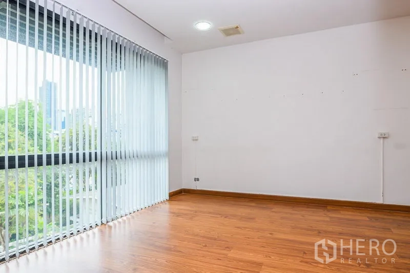 联排别墅 出租在Watthana, Bangkok - 转角房间，落地窗配百叶帘，可见城市与绿景