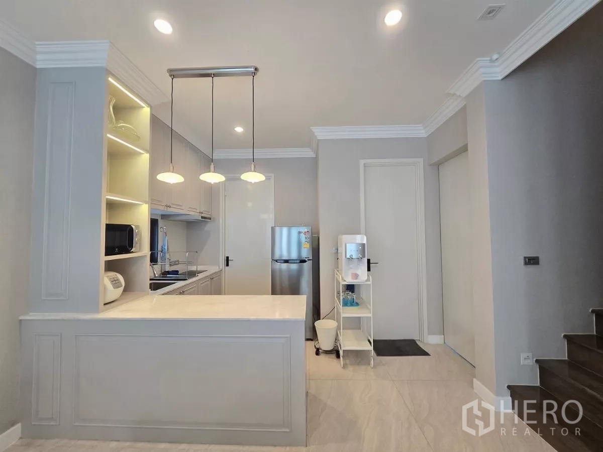 Detached House for rent in Prawet, Bangkok - Kitchen peninsula with three pendant lamps, open shelving and ample prep space.