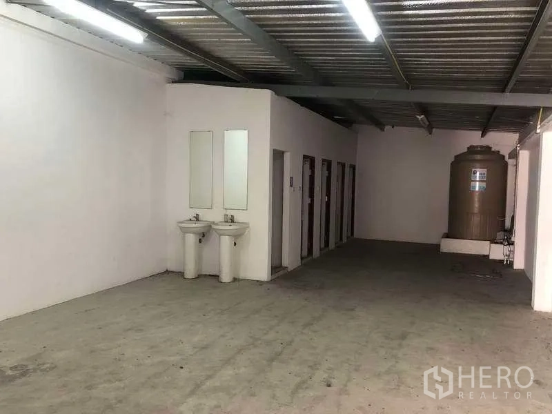 Factory for rent or sale in Bang Phli, Samut Prakan - Worker facilities area with multiple restroom stalls, twin sinks and a water tank.
