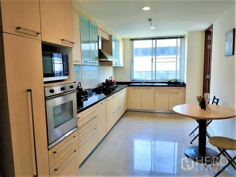 Condominium for rent in Bang Rak, Bangkok - Fitted kitchen with built-in oven, gas hob, range hood, ample cabinetry and a window-side breakfast nook.