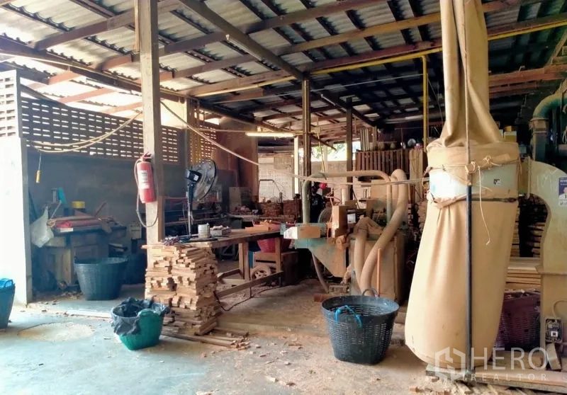 Warehouse for sale in Mueang Nonthaburi, Nonthaburi - Woodworking area with machines, dust-extraction ducts and piles of cut timber.