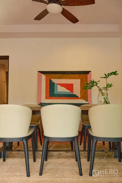 บ้าน ให้เช่าในWatthana, Bangkok - มุมห้องทานอาหาร เก้าอี้บุผ้าและงานศิลปะเรขาคณิต ใต้พัดลมเพดาน