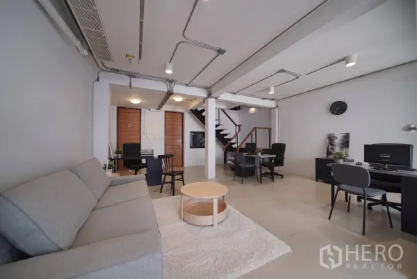 ทาวน์เฮาส์ ให้เช่าในWatthana, Bangkok - ชั้นล่างแปลนเปิดโล่ง มีโซฟา โต๊ะทำงาน และฝ้าเดินท่อโชว์