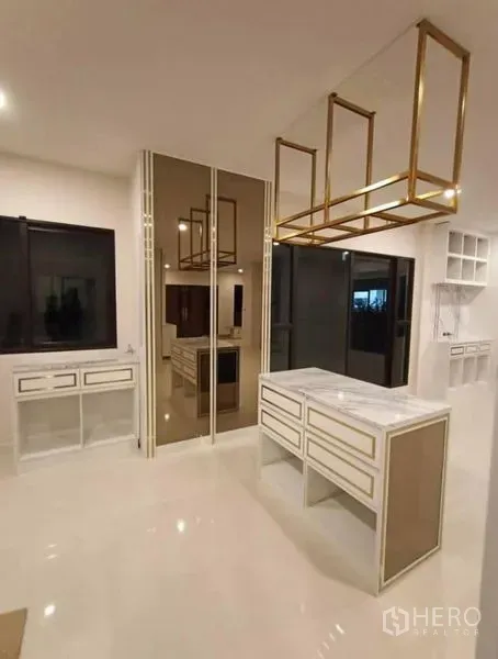 Detached House for rent or sale in Prawet, Bangkok - Modern kitchen featuring a marble island, gold accent rack and ample cabinetry.