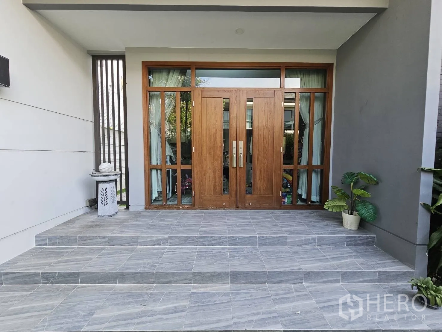 Detached House for rent in Wang Thonglang, Bangkok - Wide tiled porch with wood-framed entrance and potted plant by the doorway.