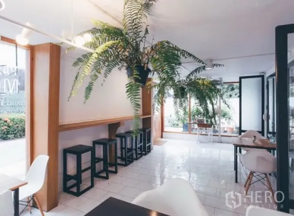 零售空间 出租在Khlong Toei, Bangkok - 明亮室内，白色地砖、吧台与高脚凳、餐桌及悬挂绿植，采光充足。