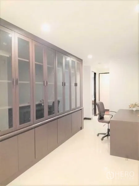 Condominium for rent in Watthana, Bangkok - Dedicated study with long desk and full-height glass-front cabinets for storage.