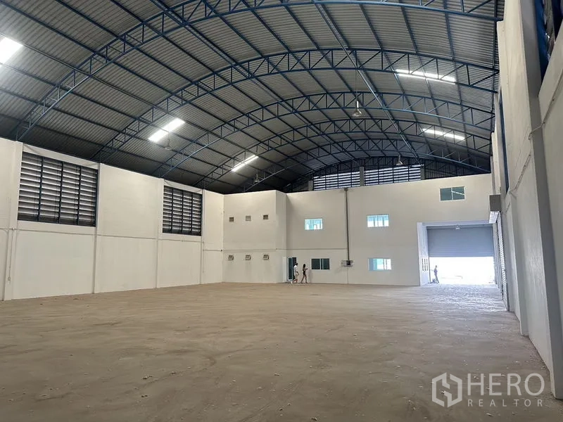 Factory for rent in Bang Bo, Samut Prakan - Open warehouse floor with arched steel truss roof, wall ventilation louvers and bright lighting.