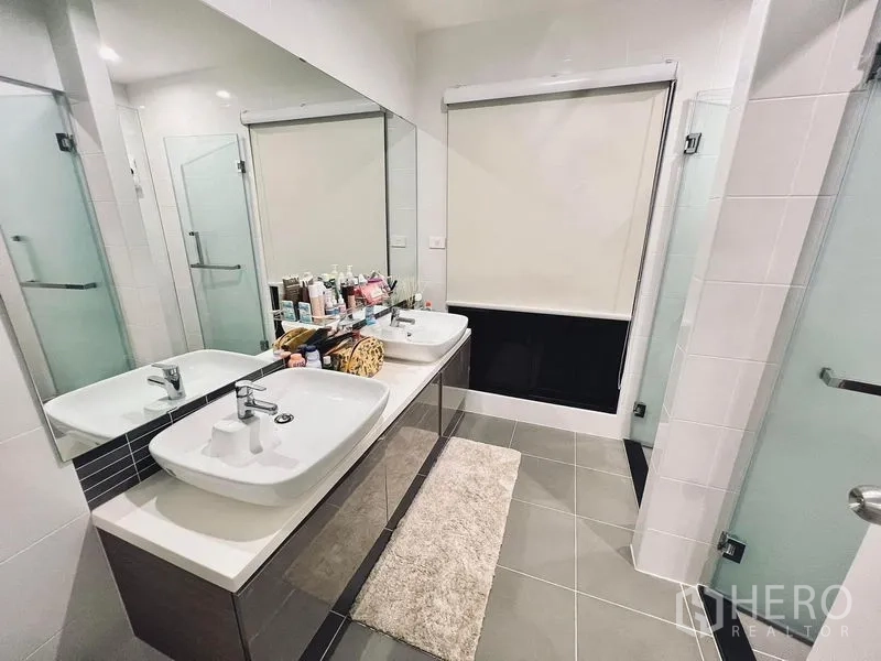 Townhouse for rent in Bang Kapi, Bangkok - Contemporary bathroom featuring a double vanity, large mirror, and glass-enclosed shower.