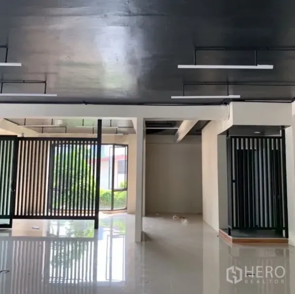 独立商业地产 出租在Khlong Toei, Bangkok - 底层开放式空间，黑色天花与线性灯具，玻璃与格栅隔断，布局灵活。