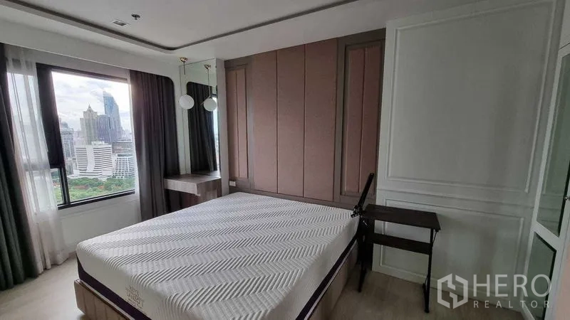 Condominium for sale in Pathum Wan, Bangkok - Master bedroom with large windows, paneled accent wall and skyline view