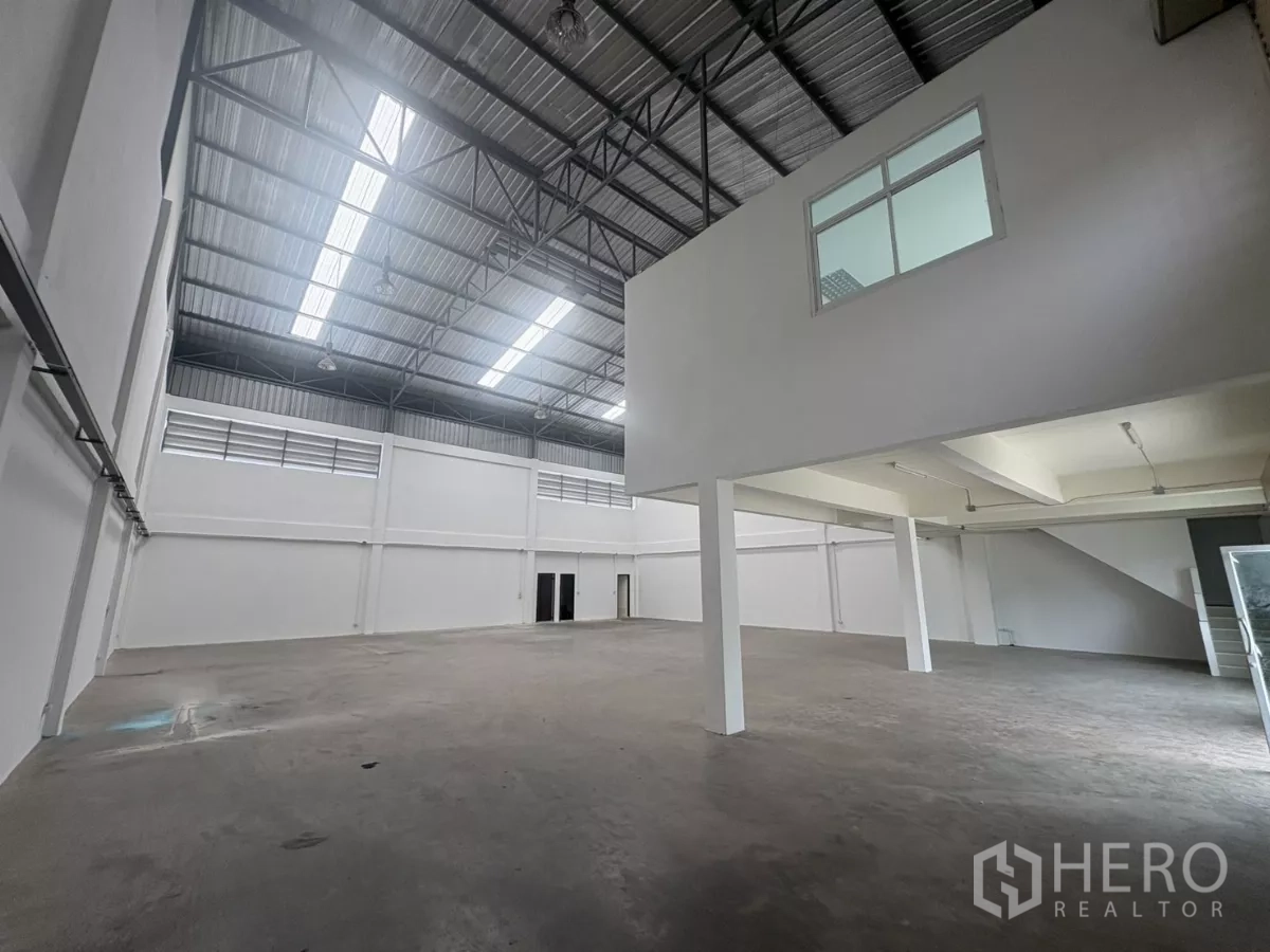 工厂 出租在Phra Samut Chedi, Samut Prakan - 宽敞仓库内部，高钢结构屋顶与采光天窗，带夹层办公室。
