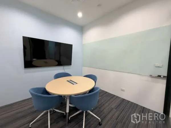 Office Space for rent in Huai Khwang, Bangkok - Compact meeting room with round table, four blue chairs, wall‑mounted screen and glass whiteboard.