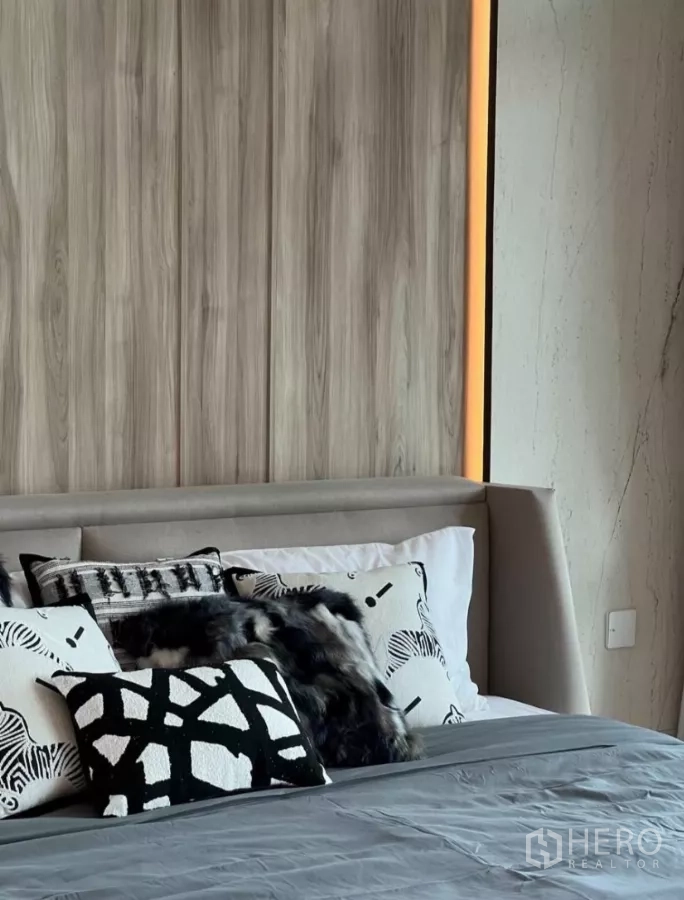 Detached House for rent in Samut Prakan - Close-up of wood-paneled headboard with warm LED strip and monochrome cushions.