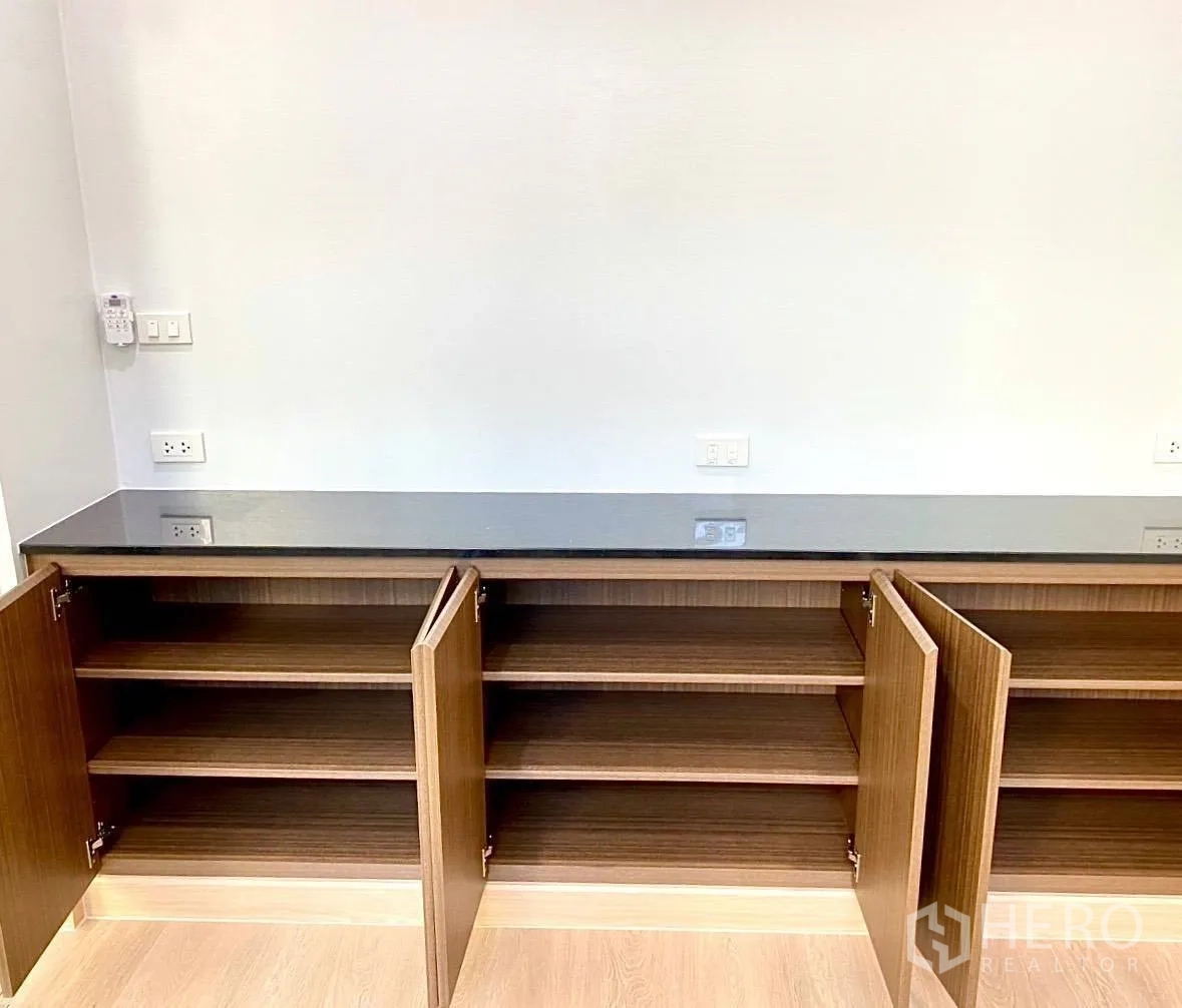 Office Space for rent - Low built-in cupboards open to reveal shelving and power outlets above.