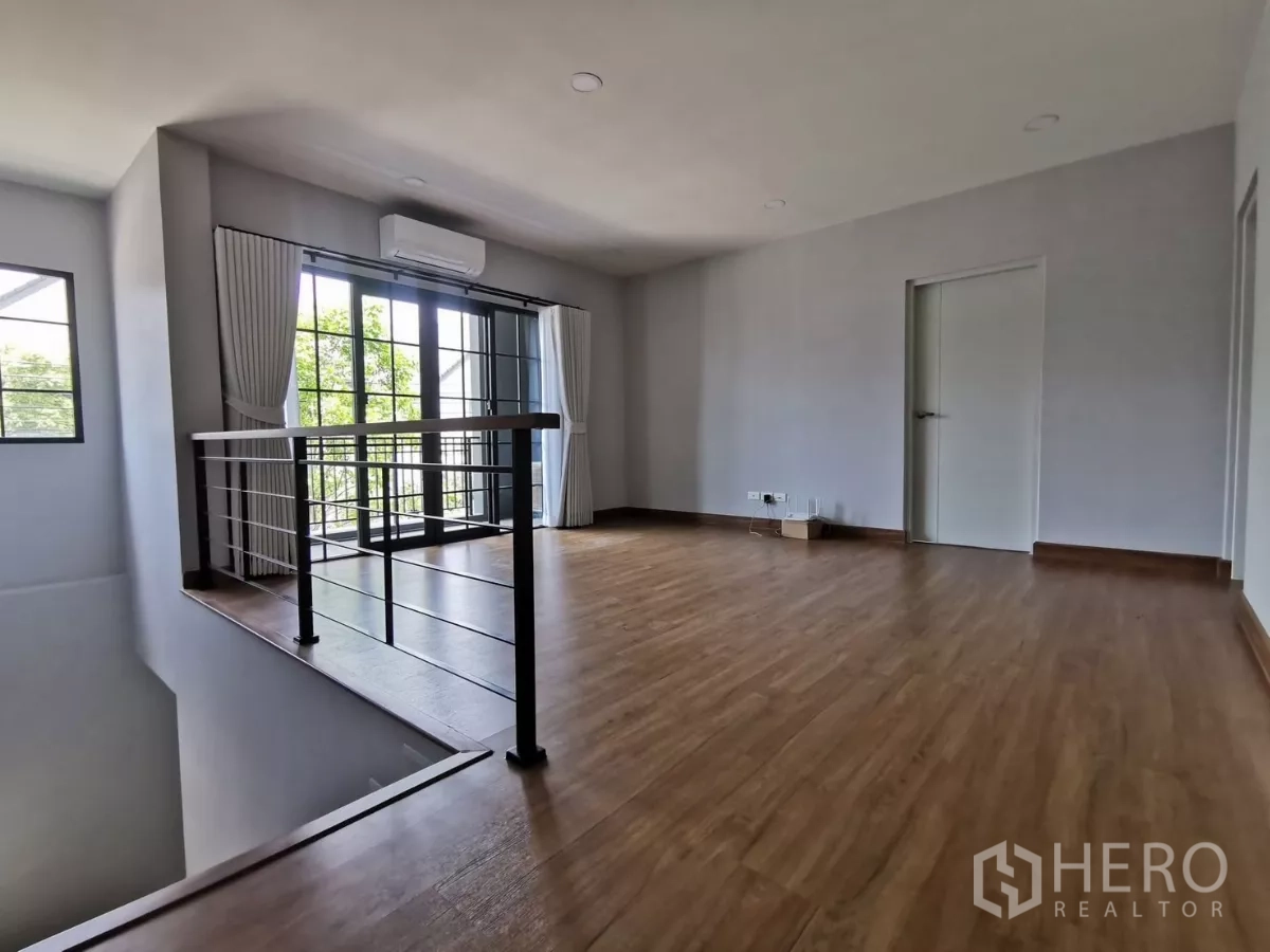 Detached House for rent in Bang Phli, Samut Prakan - Upstairs family area with balcony doors, metal railing and wood floors.